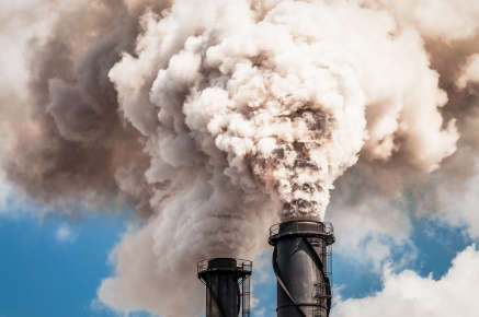 A pair of black factory cooling towers billowing pollution.