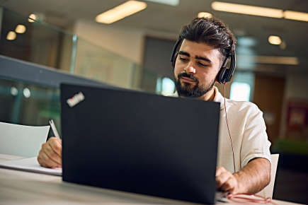 Person working on a laptop and writing something