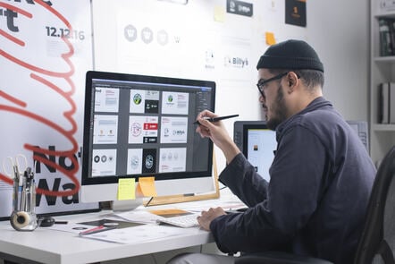 Graphic designer sitting at a desk drawing on his Apple computer.