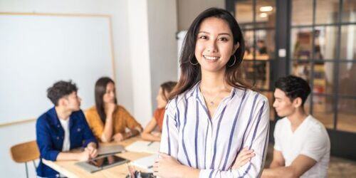 Woman smiling, stood in a work office.