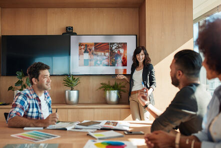 Young professionals in a meeting with a woman presenting to the team.