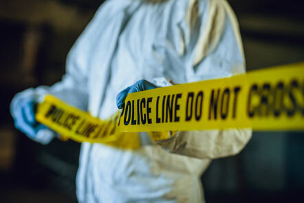 A forensic scientist pulling yellow police tape around a crime scene.