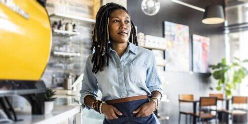 Woman leaning against the counter in a coffee shop. 