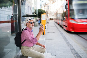 Older man with vision impairment waits for a tram