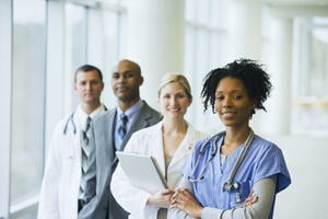 2 happy female wearing medics' uniforms standing before 2 male multi-ethnic medical professionals.