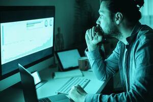 Male professional sat at a desk looking at graphs on a computer screen