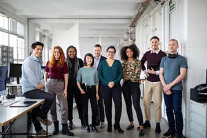 Multi-ethnic business group standing together in the office. Portrait of successful business professionals in an open plan office.