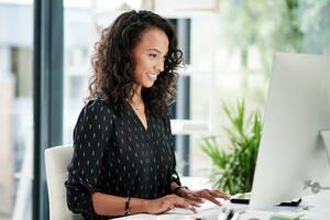 Shot of a young businesswomen using a computer at her desk in a modern office doing web application testing.