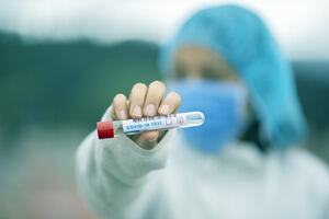 A person holding a sample tube labelled as COVID-19 test negative