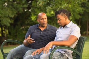 An adult talking to a young person in a supportive way.