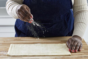 Hand sprinkling sugar on pastry