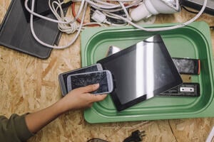 Directly above shot of a worker with old smart phone and tablets at table for recycling