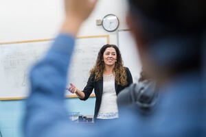 A female teacher standing at the front of a class, teaching mathematical concepts,  probability and statistics.