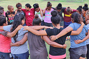 Girls connected in circle, linking arms around each others shoulders