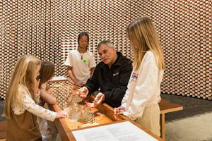 An educator and students exploring artefacts in He Whakamaumaharatanga at the Waitangi Treaty Grounds.