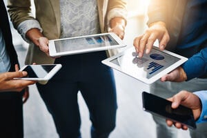 Group of people holding tablets showing data