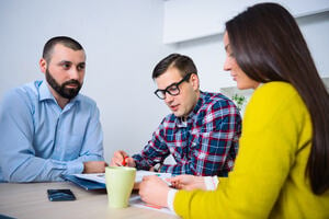 Group of diverse people sat at a table discussing paperwork.