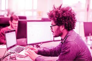 Male professional looking at his laptop behind a desk in an office  environment