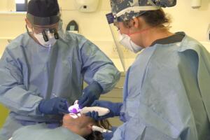 A dentist and vocational trainee providing treatment for a patient