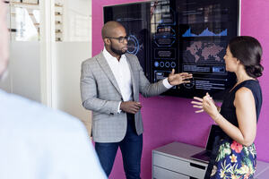 Businessman and woman using graphs on screen in meeting