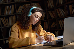 Woman sat in front of laptop making notes