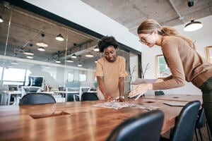 Two women in an office looking over a table discussing behaviour change